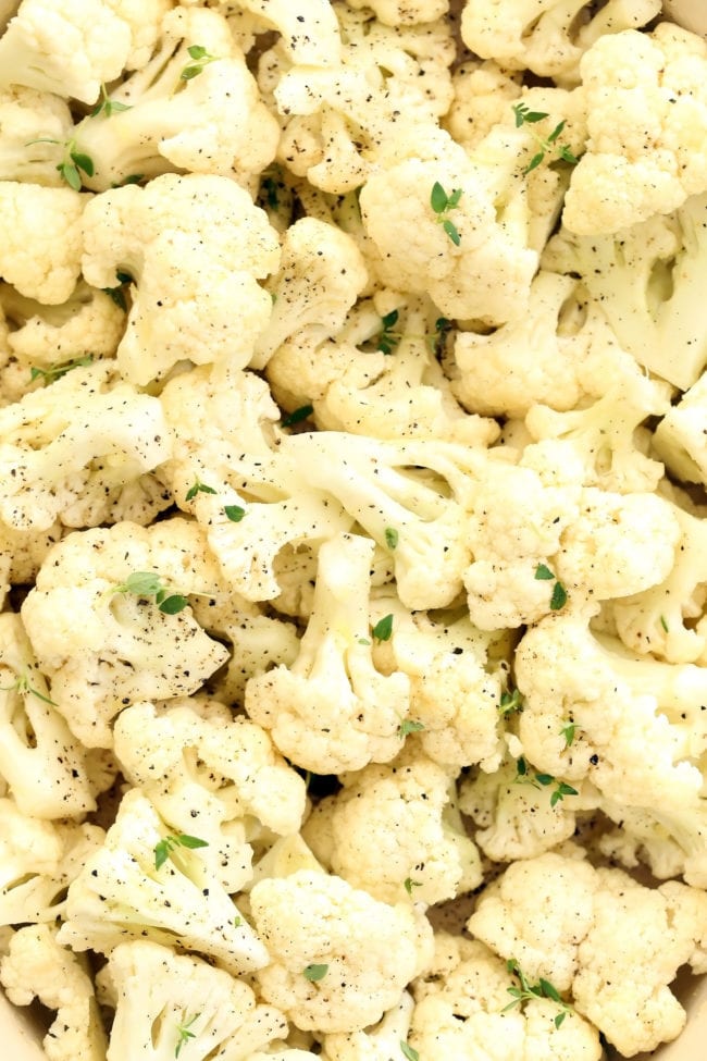 A roasting dish filled with pieces of cauliflower seasoned with black pepper