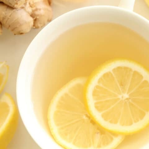 A white cup of ginger tea with lemon.