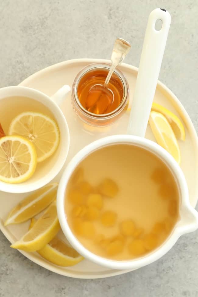 A white cup of ginger tea with lemon slices