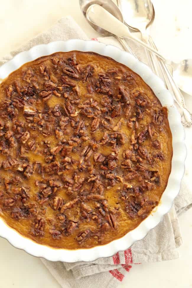 A white pie dish filled with a creamy dessert topped with toasted nuts.