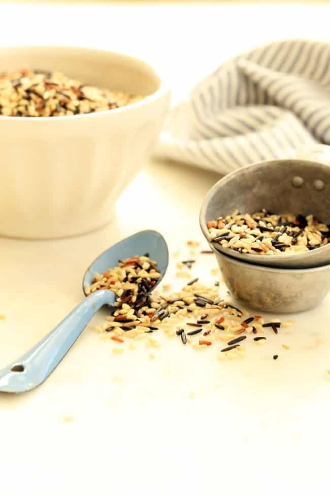 A white bowl and measuring cup filled with wild rice.