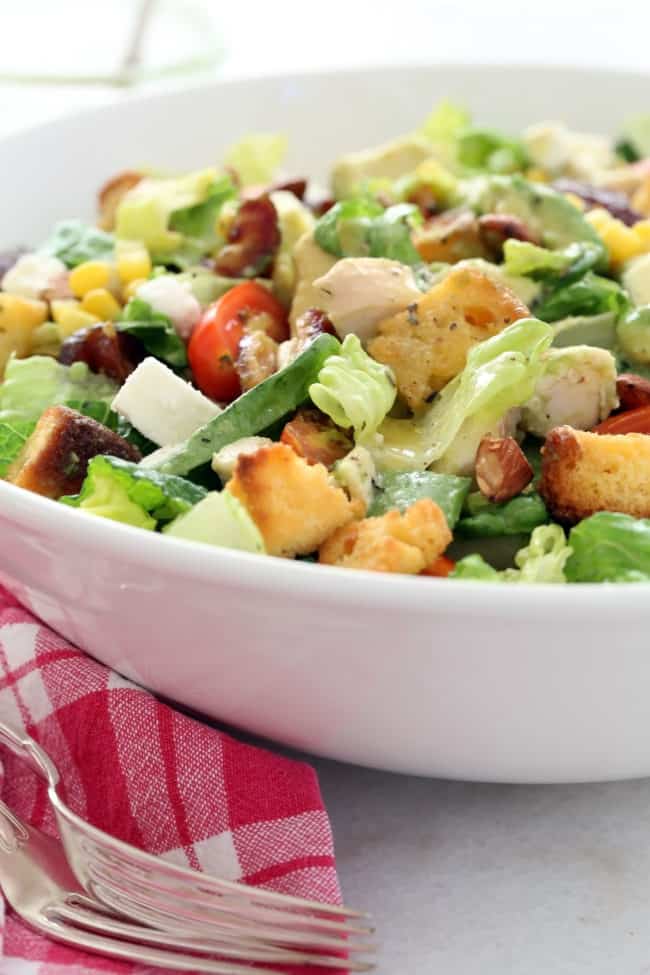 This Chicken Avocado Chopped Salad  is loaded with chopped chicken,  avocado, corn,, cornbread croutons, dates, almonds, tomatoes and goat cheese