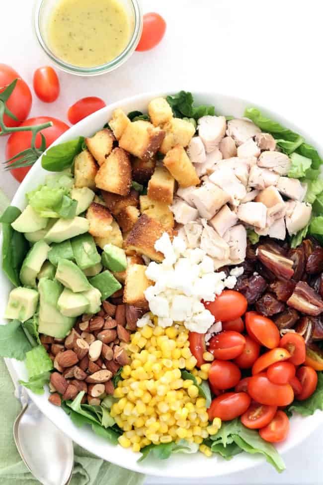This Chicken Avocado Chopped Salad  is loaded with chopped chicken,  avocado, corn,, cornbread croutons, dates, almonds, tomatoes and goat cheese