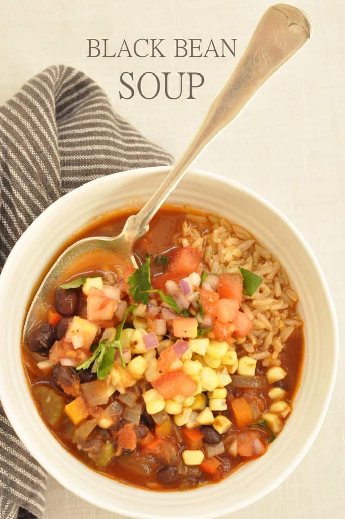A white bowl filled with black bean soup. A spoon rests in the bowl.