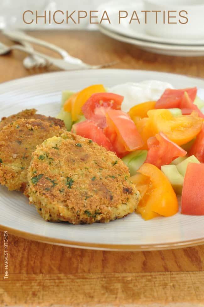 A white plate filled with chickpea patties and tomato wedges.