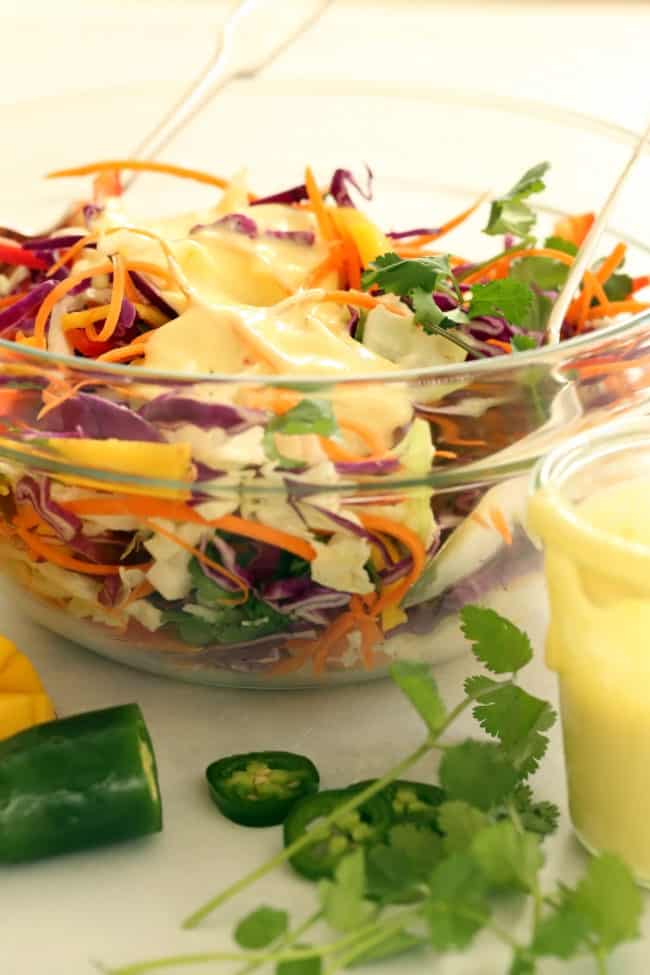 A clear glass bowl of homemade mango cabbage slaw with citrus dressing.
