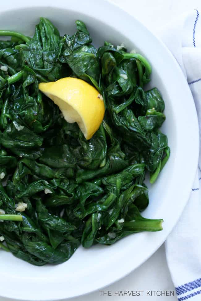 A white plate filled with cooked green vegetables.