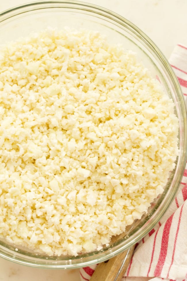 A clear glass bowl filled with riced cauliflower.