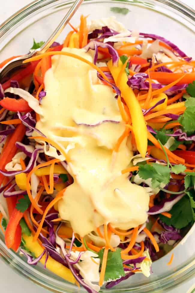 A clear glass bowl with cabbage mango slaw.