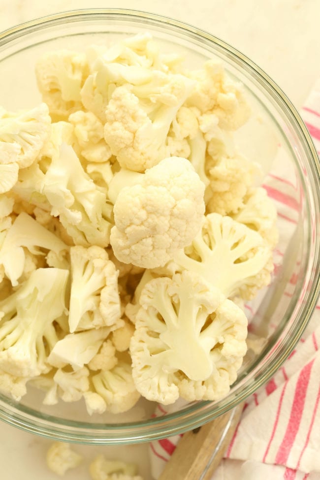 A clear glass bowl filled with chopped cauliflower.