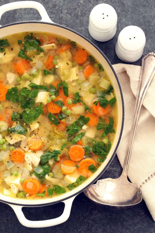 A white pot filled with Spring Chicken Vegetable Soup.