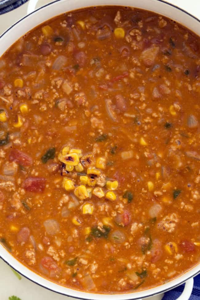 This easy taco soup combines  ground turkey, refried beans, tomatoes and tortillas and simmers it all in a deliciously rich broth seasoned with classic Mexican flavors