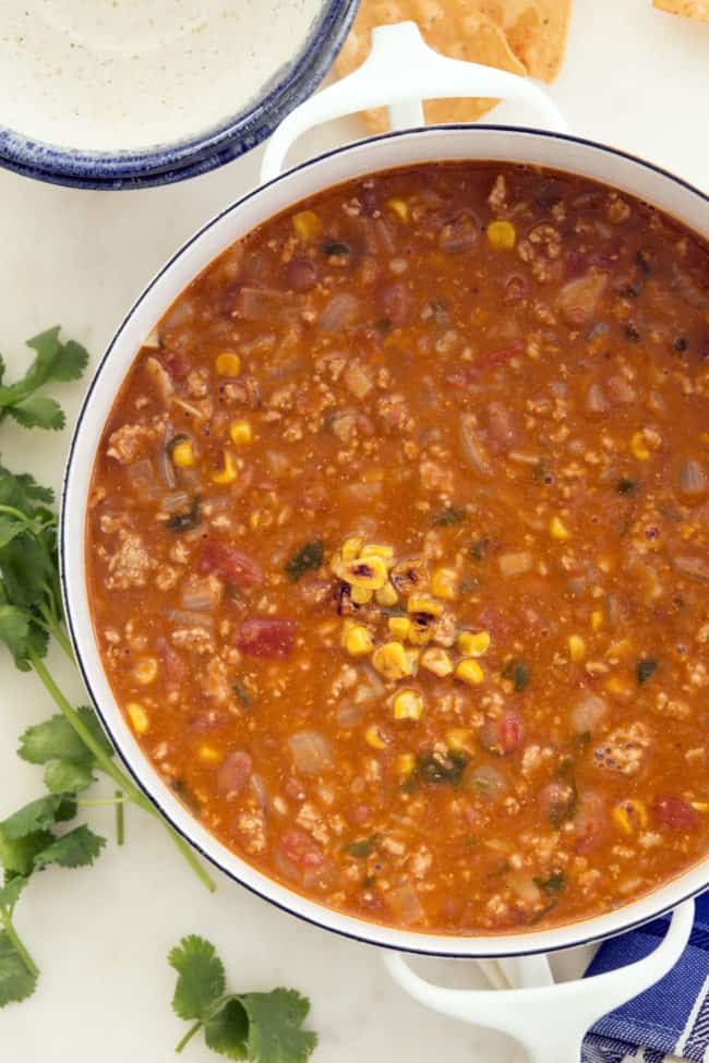 This easy taco soup combines  ground turkey, refried beans, tomatoes and tortillas and simmers it all in a deliciously rich broth seasoned with classic Mexican flavors