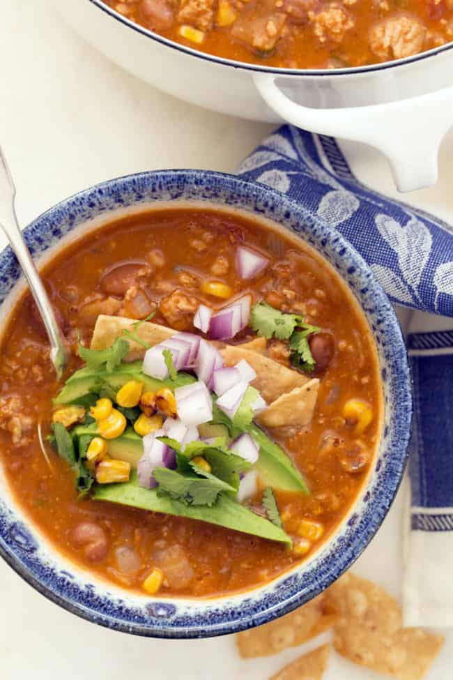 This easy taco soup combines  ground turkey, refried beans, tomatoes and tortillas and simmers it all in a deliciously rich broth seasoned with classic Mexican flavors