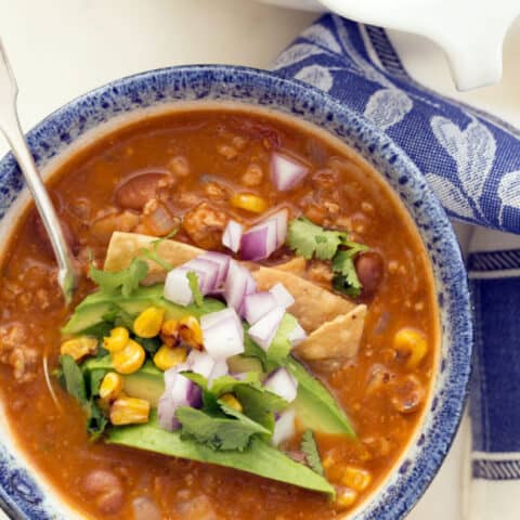 This easy taco soup combines  ground turkey, refried beans, tomatoes and tortillas and simmers it all in a deliciously rich broth seasoned with classic Mexican flavors