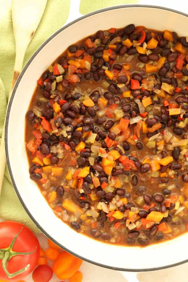 A white pot filled with black bean stew.