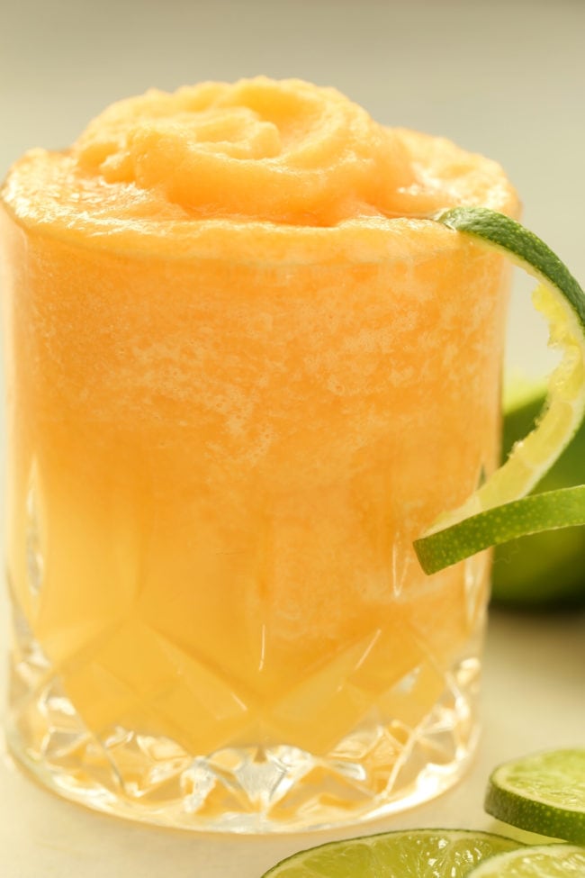 A clear drinking glass filled with cantaloupe slush.