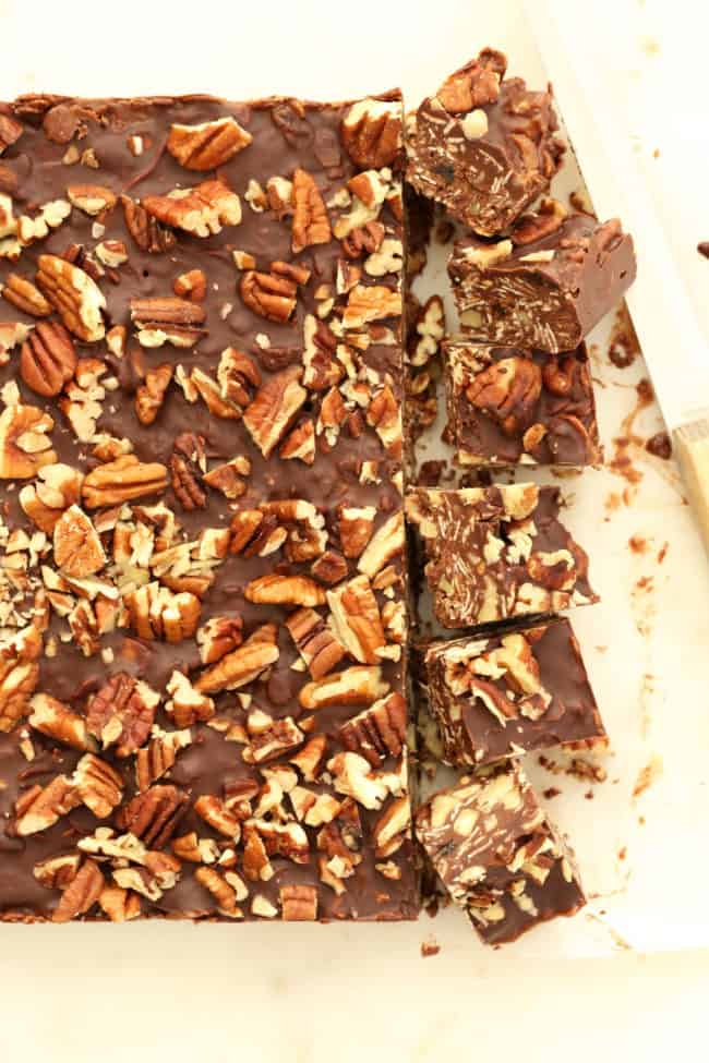 Chocolate oat squares set on parchment paper with a knife next to them.