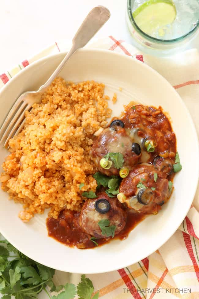 A white plate of Mexican meatballs in enchilada sauce with Spanish rice.