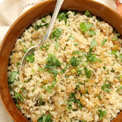 A brown bowl filled with caramelized onion quinoa.