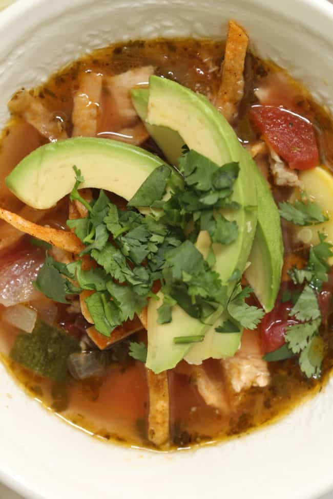 A white bowl filled with soup with avocado