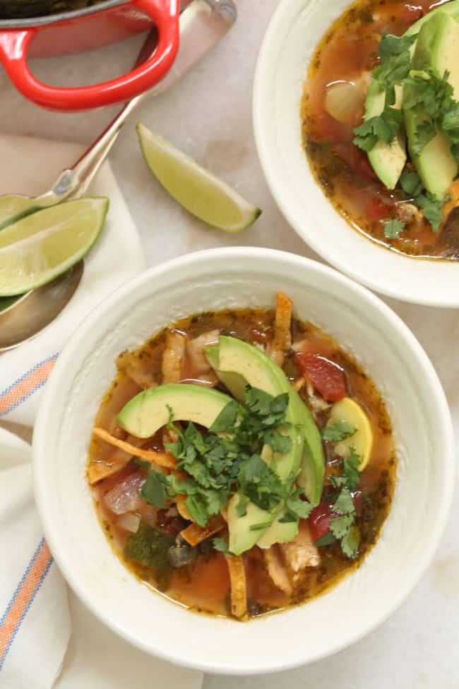 Two white bowls filled with chopped chicken and vegetables in broth