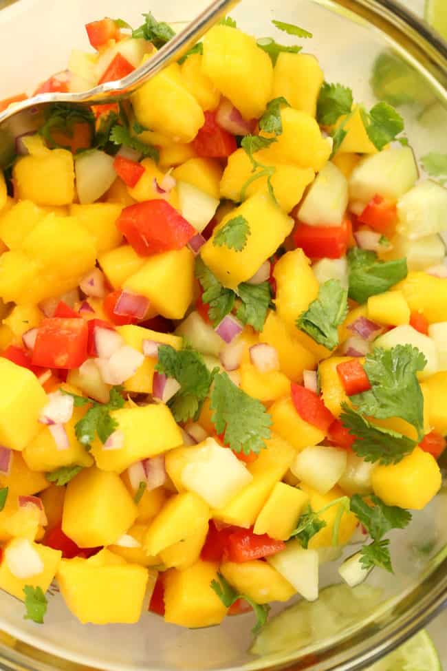 A clear glass mixing bowl filled with Mango Salsa.
