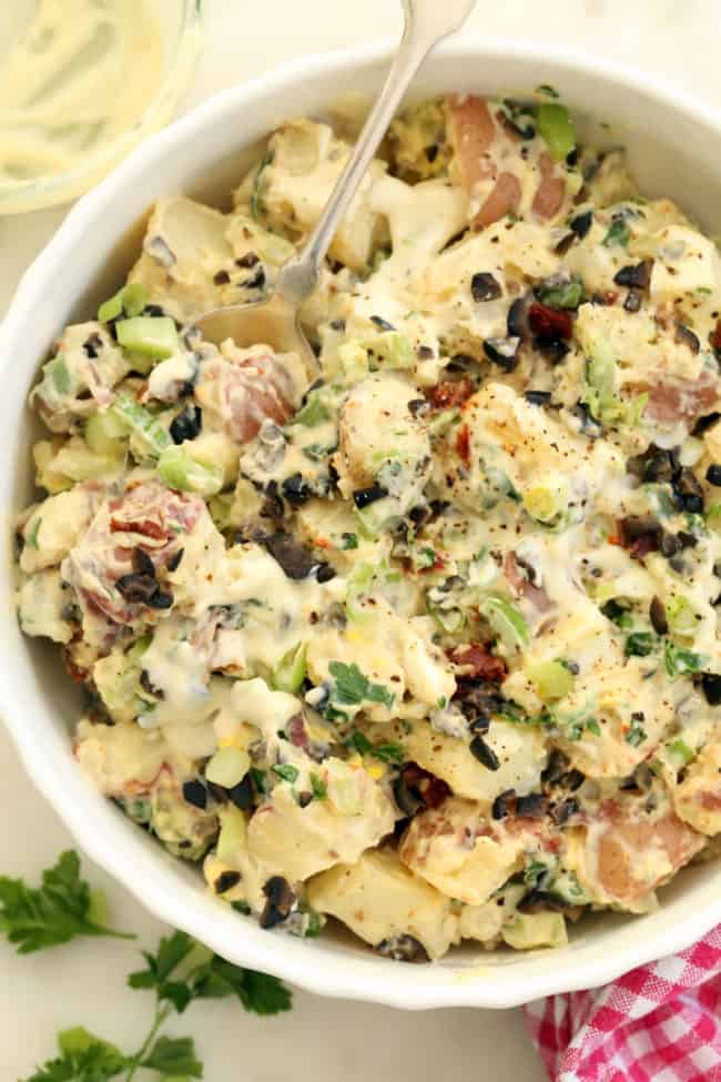 A white bowl filled with roasted garlic potato salad.