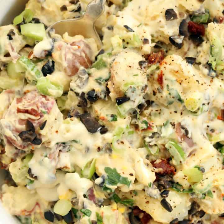 This Roasted Garlic Potato Salad is made with red potatoes, hard-boiled eggs, celery, green onions,  black olives and sun-dried tomatoes.  And it's all tossed in an amazing creamy roasted garlic dressing