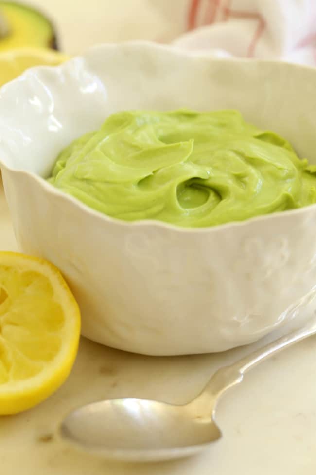 A white bowl filled with a green sandwich spread.