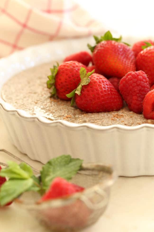 A white baking dish filled with a chilled dessert. Strawberries garnish the dessert.