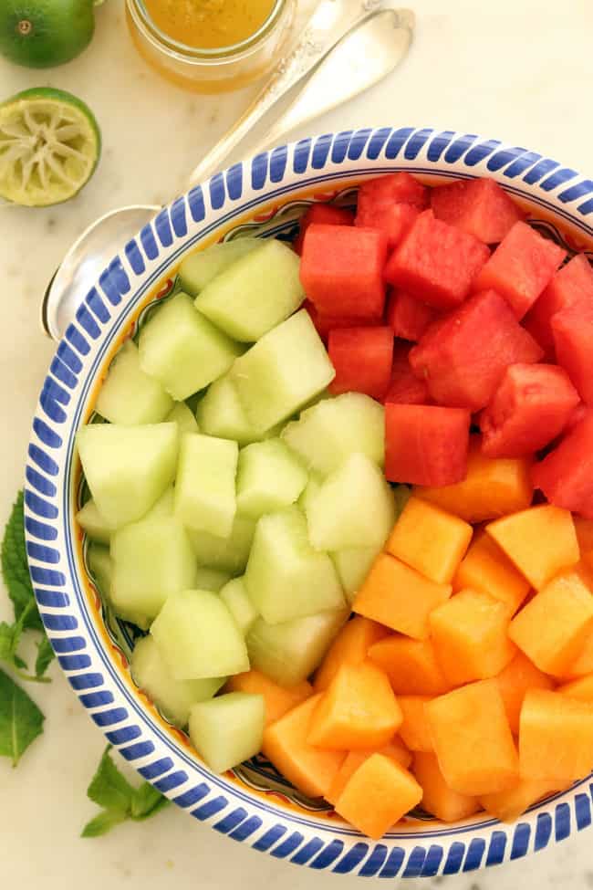 A blue and white bowl of cut fruit.