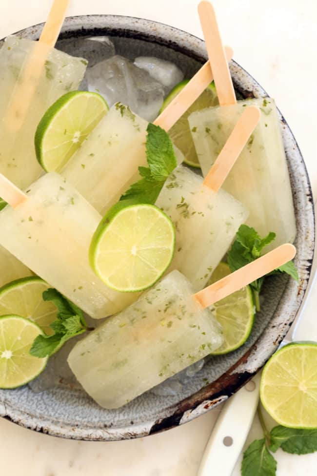 A gray dish filled with mint and lime popsicles.