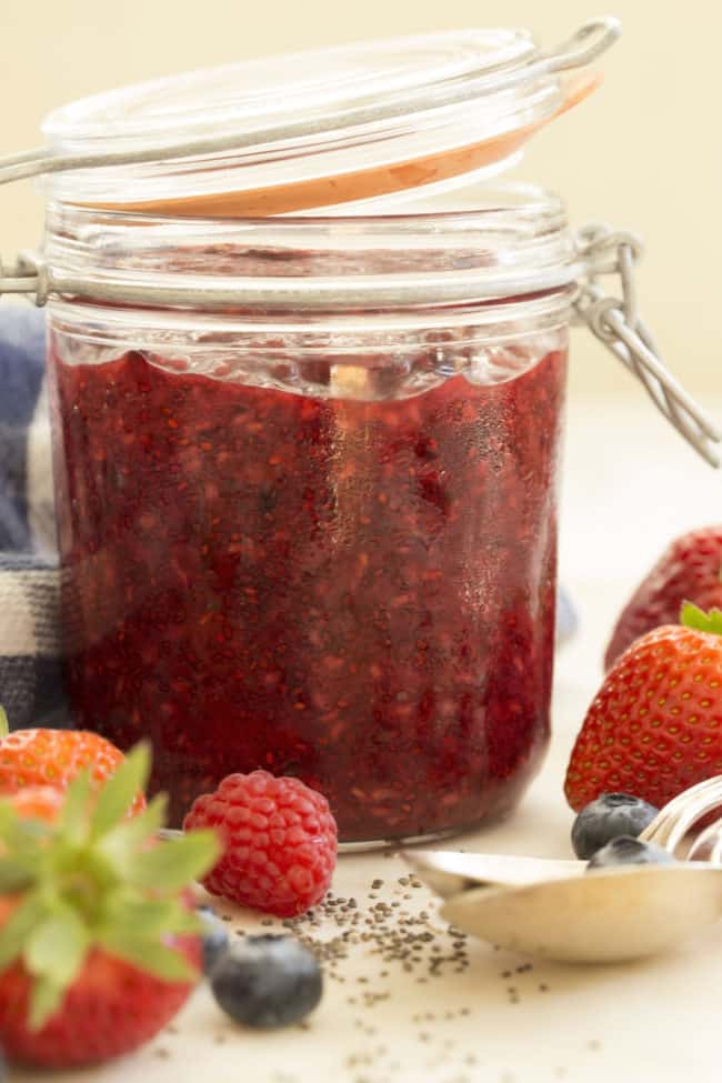 A clear glass mason jar filled with mixed berry chia seed jam.