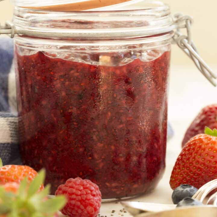 A clear glass mason jar filled with mixed berry chia seed jam.