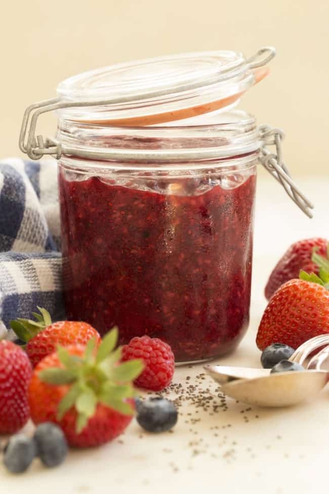 A clear glass mason jar filled with mixed berry chia seed jam.