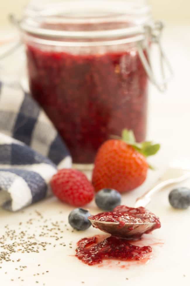 A clear glass mason jar filled with fruit preserves.