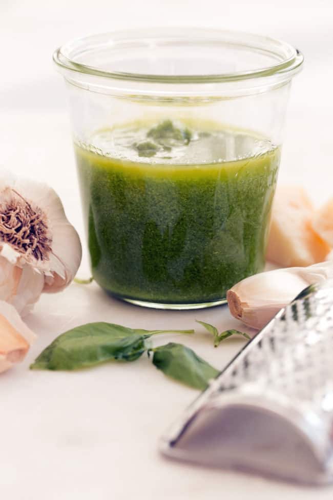 A clear glass jar filled with green herb sauce.