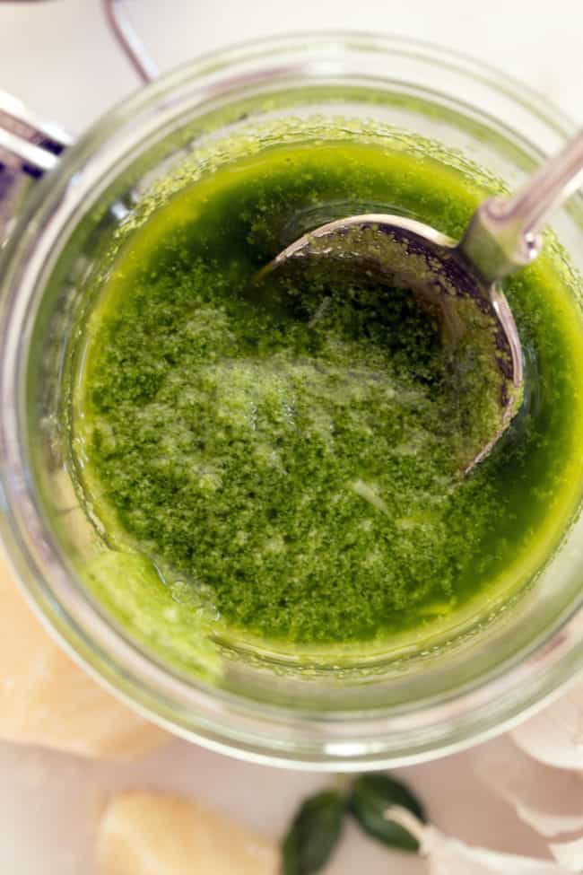 A glass jar filled with green herb sauce