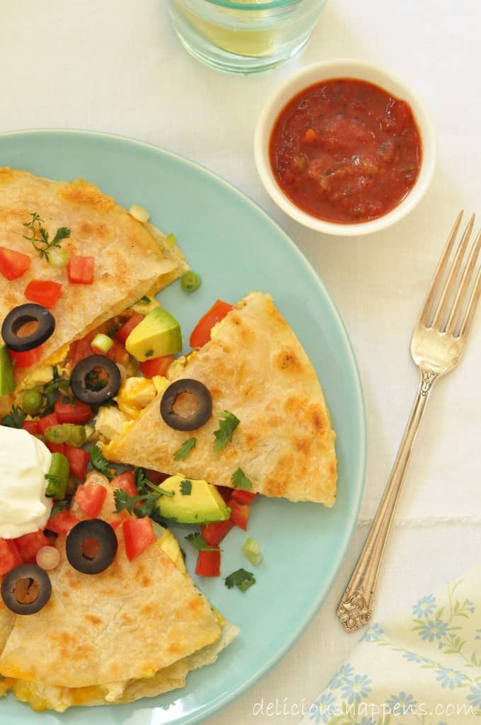 A green plate filled with flour tortilla stuffed with scrambled eggs.
