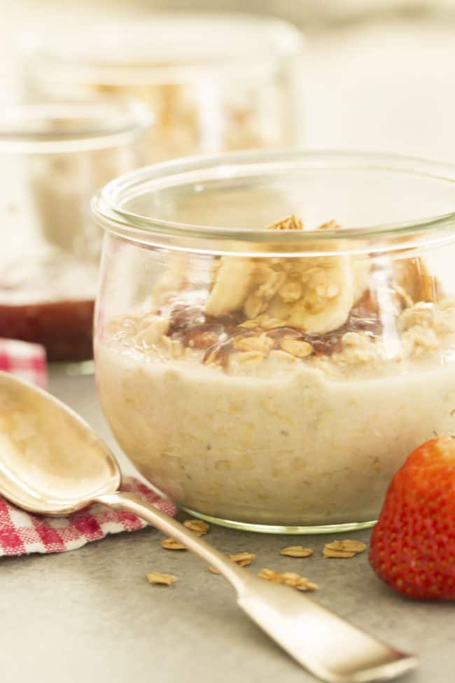 A glass jar filled with cereal and bananas.
