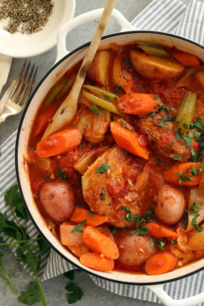 A white Dutch oven filled with cooked chicken and vegetables stew called Chicken Continental.