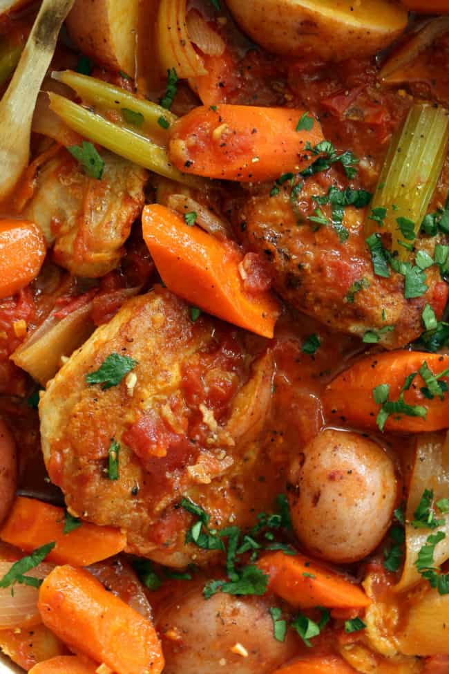 A white pot filled with cooked chicken and mixed vegetables for a stew called Chicken Continental.