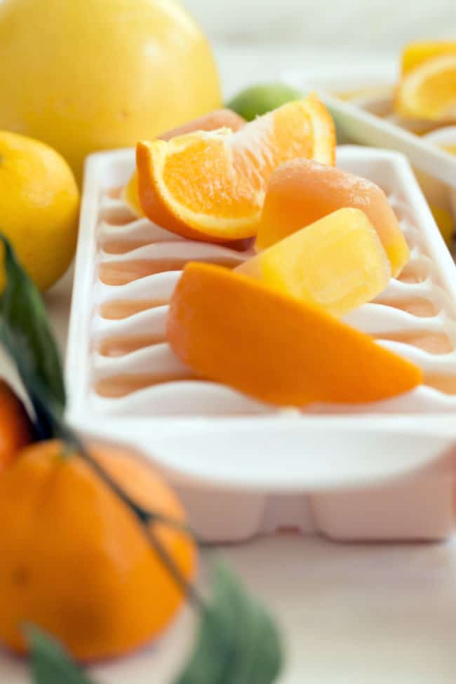 A white ice cube tray filled with grapefruit and orange juice ice cubes.