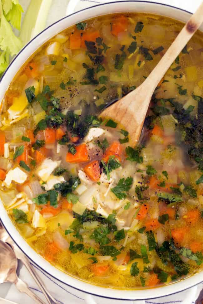 A white pot filled with Roasted Garlic Chicken Soup.