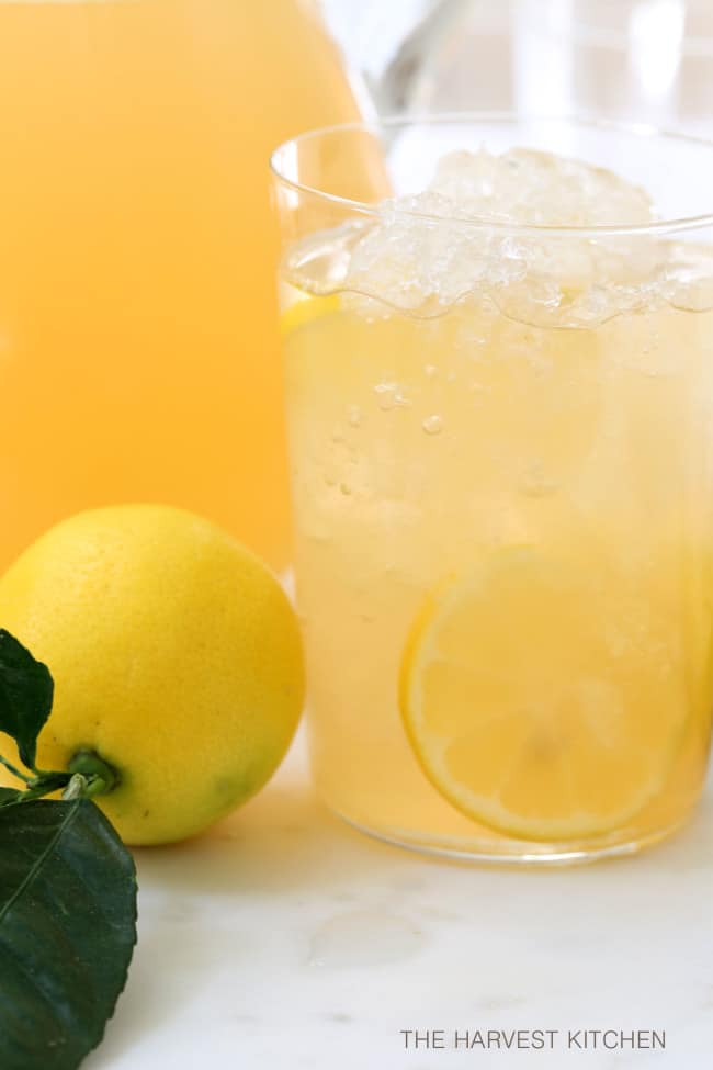 A clear dinking glass filled with iced apple green tea.