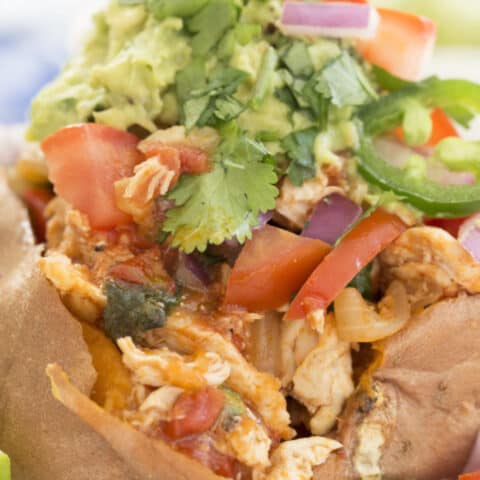 A Mexican chicken stuffed sweet potato on a white plate.