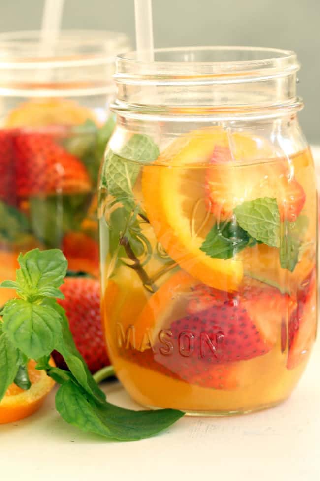 Two mason jars filled with liquid and fruit.