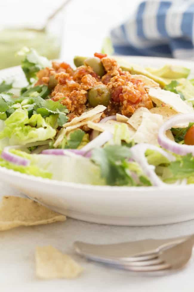 White bowl with tossed salad topped with cooked ground chicken