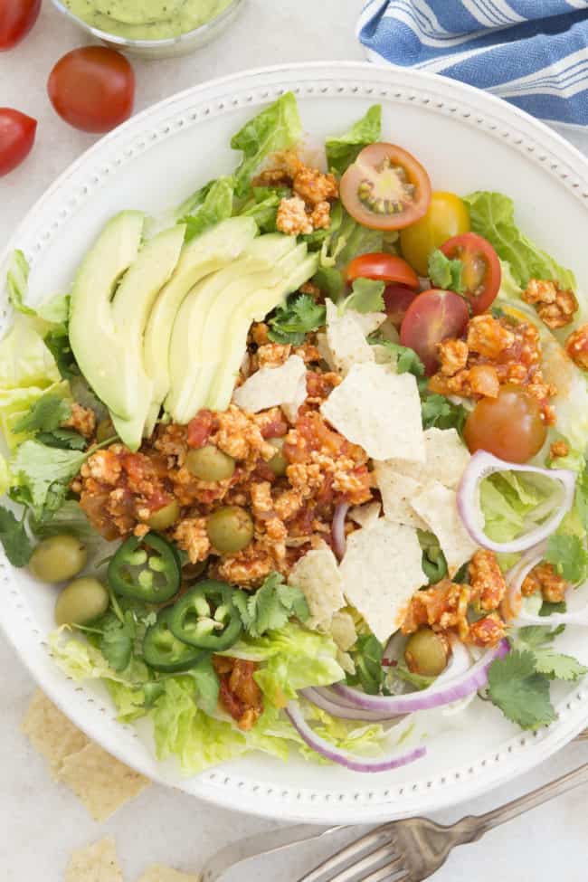 White bowl with tossed salad topped with Cuban picadillo recipe.